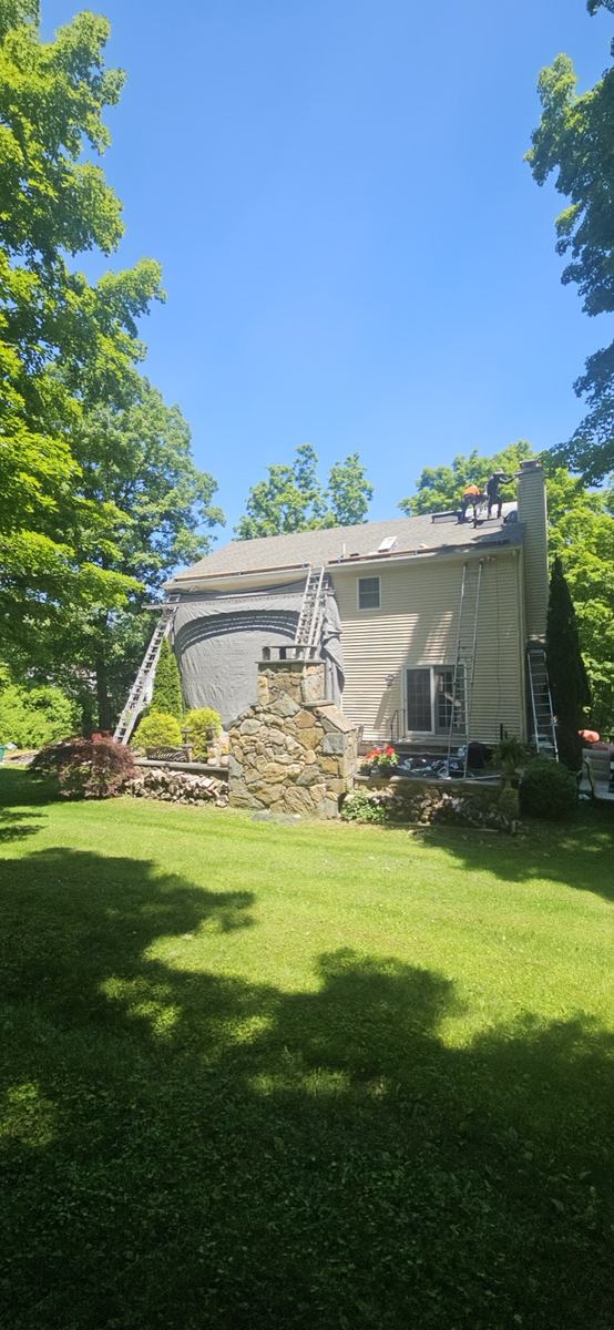 Crew re-roofing a home with a stone chimney