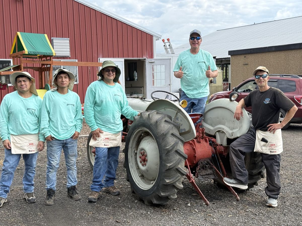 The Andy's Roofing crew with a vintage tractor at the barn