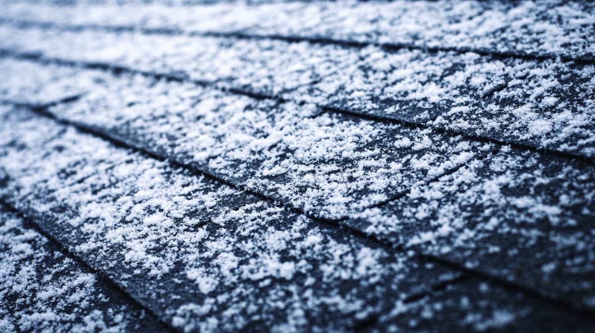 Fresh snow across dark asphalt shingles