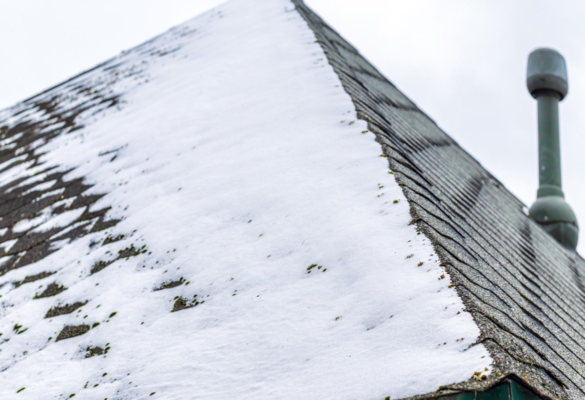 Snow packed along the edge of a shingled roof